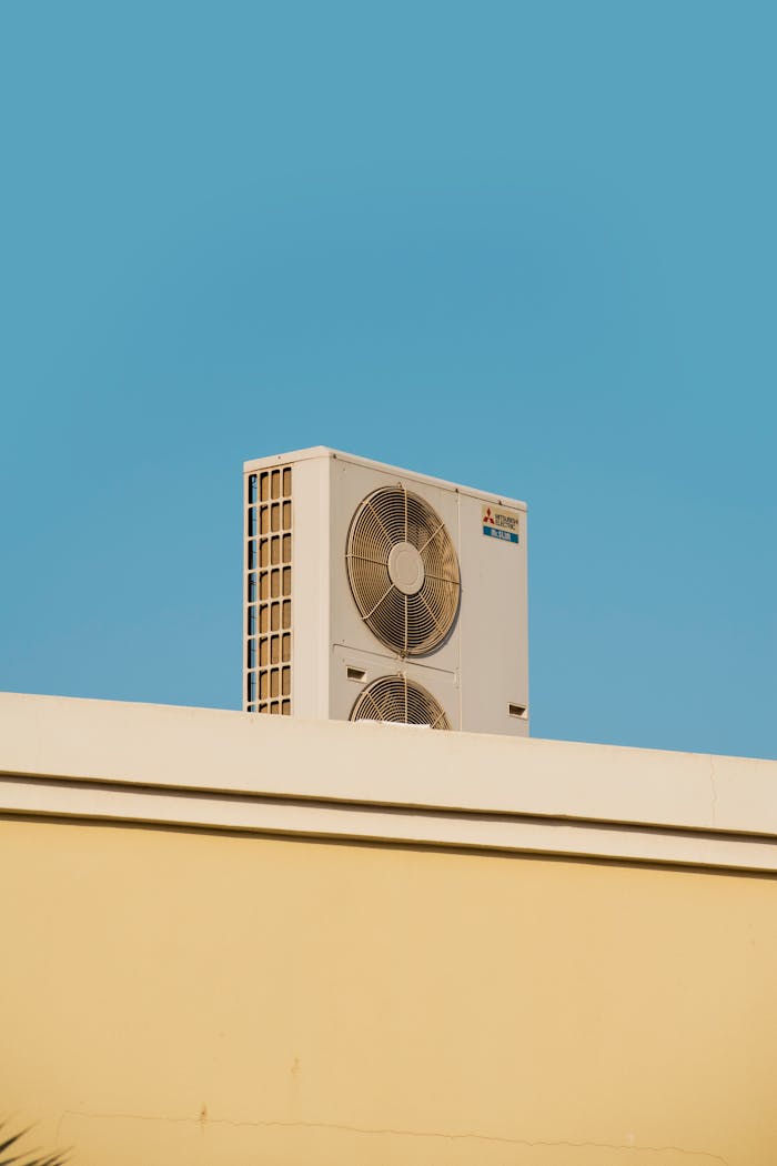A simple and modern air conditioner unit on a rooftop with a blue sky backdrop in Dubai.