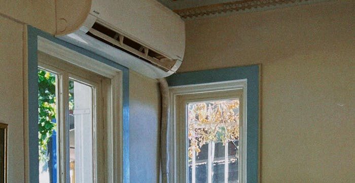 Un phonographe vintage est posé sur un escalier intérieur, à côté de fenêtres laissant entrer la lumière naturelle.