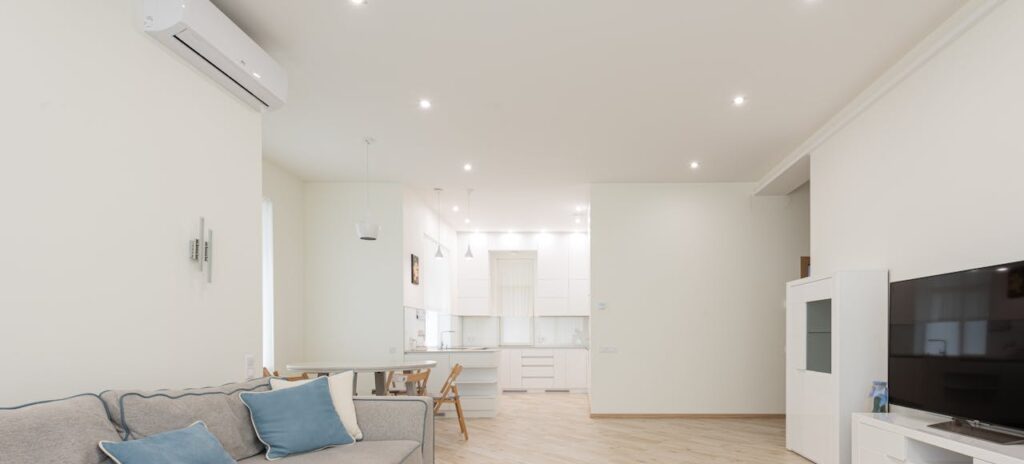 Appartement moderne avec un salon spacieux équipé d’une télévision et un sol stratifié neuf et propre, sous des lumières vives et lumineuses.